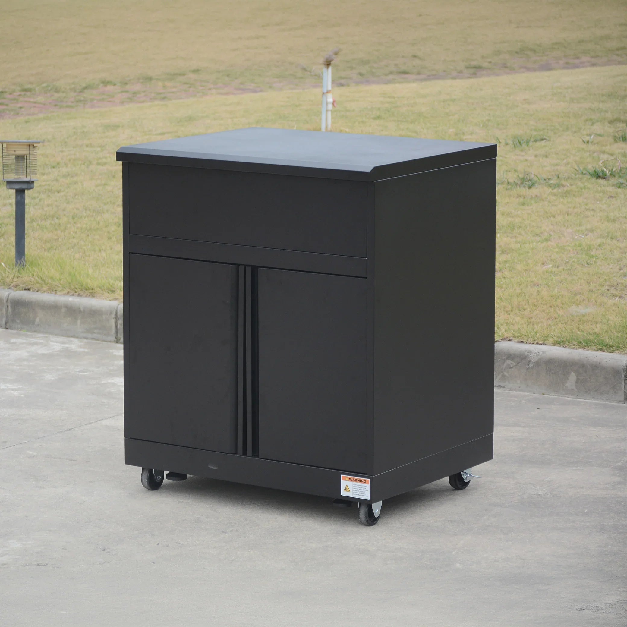 Black metal storage cabinet on wheels outdoors, modern utility furniture