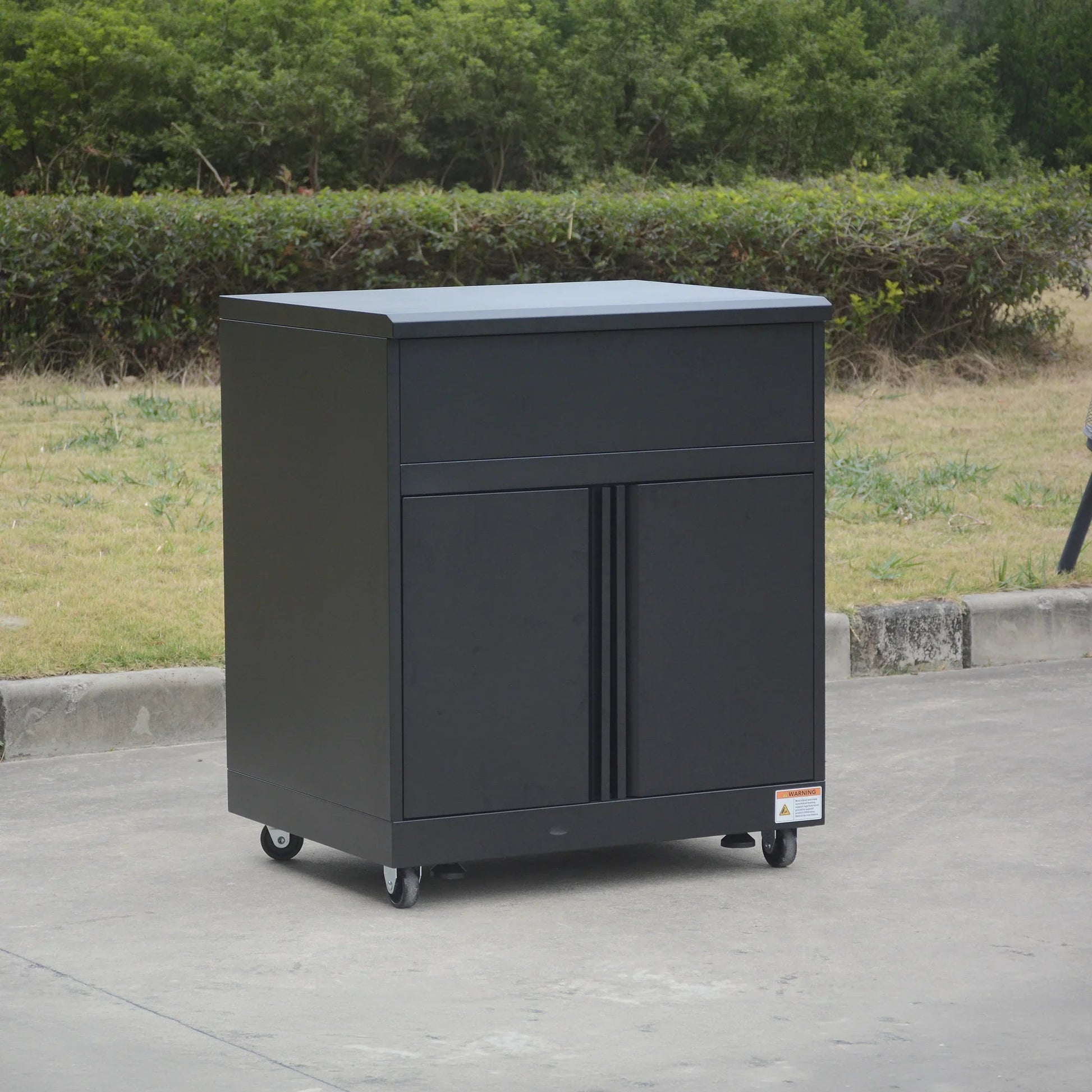 Black metal storage cabinet with wheels, outdoor setting, modern minimalist design.