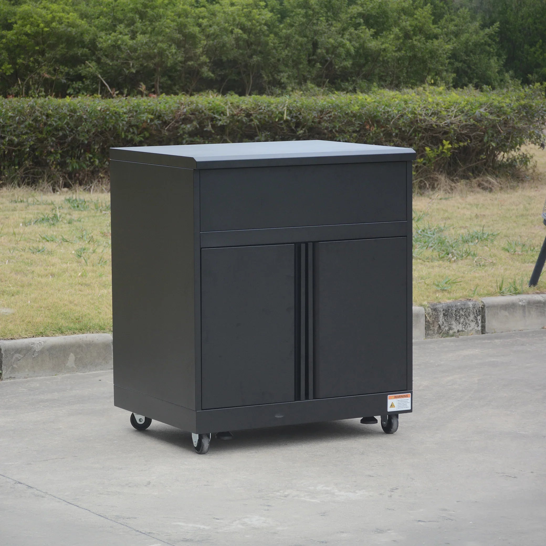 Black metal storage cabinet with wheels, outdoor setting, modern minimalist design.