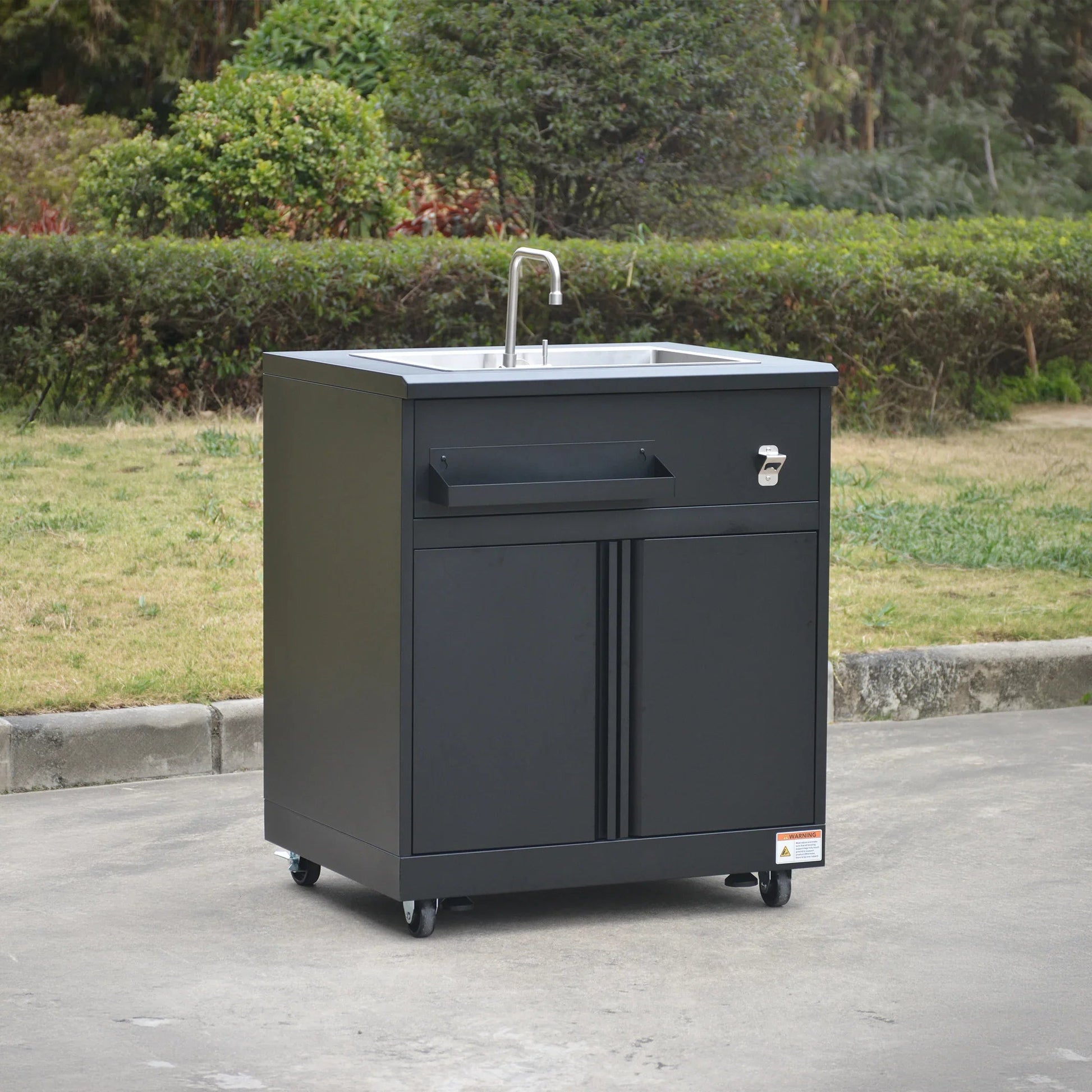 Black outdoor mobile sink cabinet with faucet and storage on wheels in garden setting