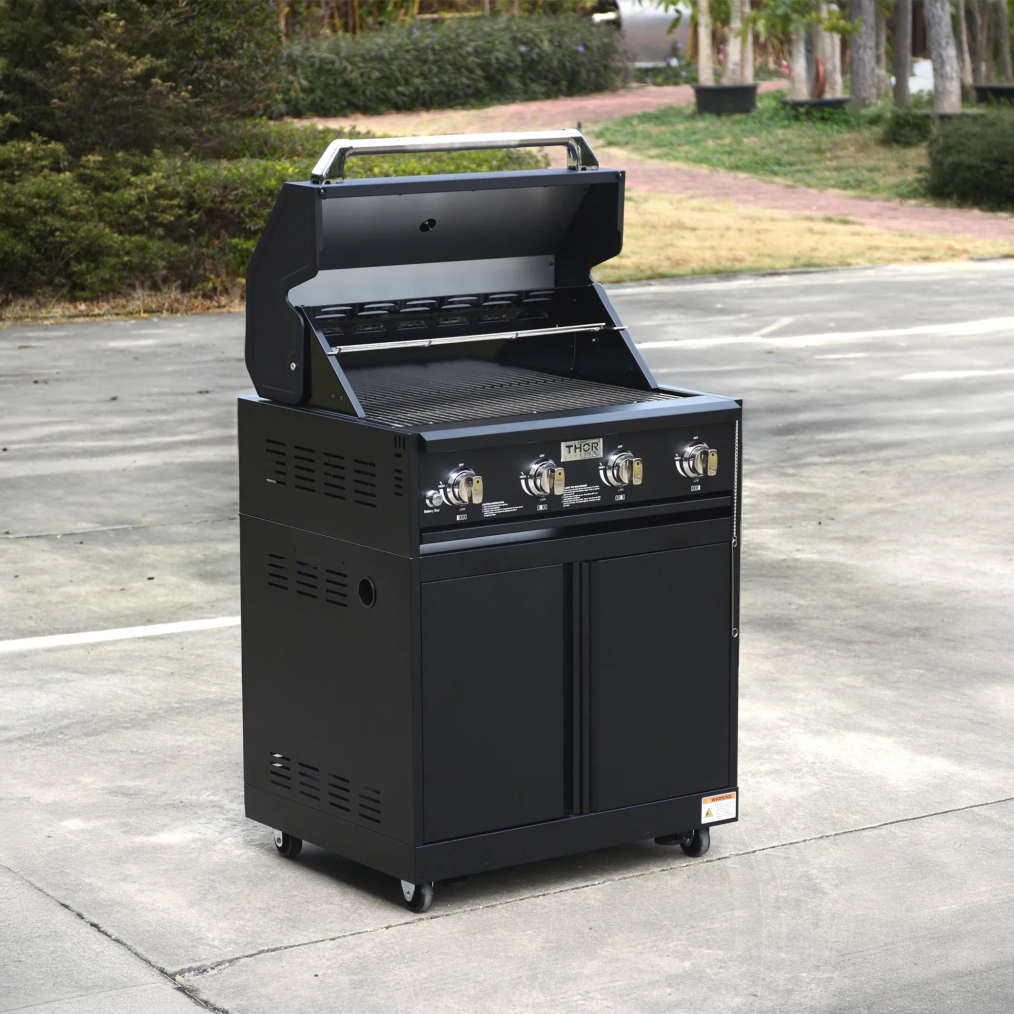 Black outdoor gas grill with four burners and open lid on a patio area