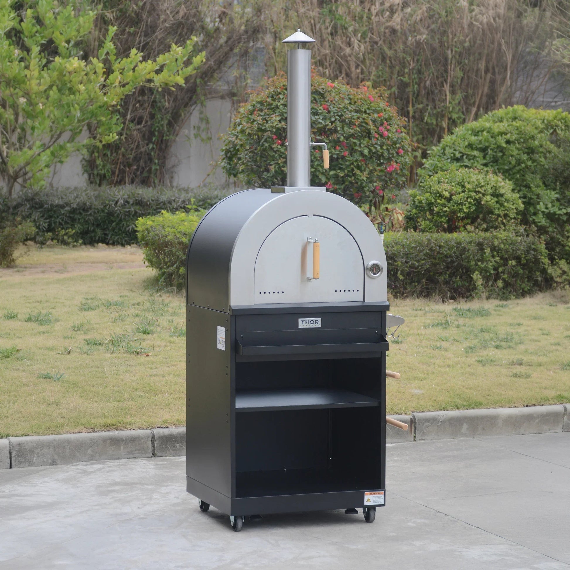 Outdoor wood-fired pizza oven with chimney, stainless steel door, and storage shelves on wheels